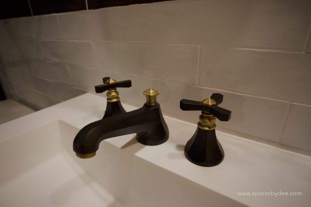 black faucet feature in Dramatic bathroom with black, white and gold accents.