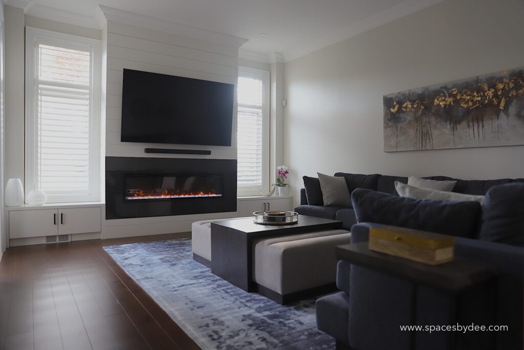 modern living family room with blue sectional and bold black and white fireplace, wall art and decor.