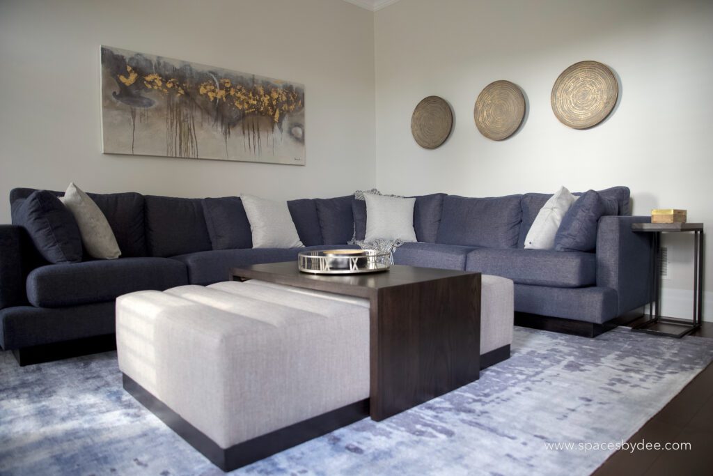 modern living family room with blue sectional and bold black and white fireplace, wall art and decor.
