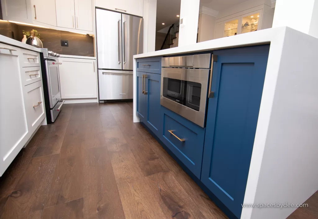 beautiful moody and bold kitchen with black, white, cream and gold accents with a bold backsplash and brown wood flooring.