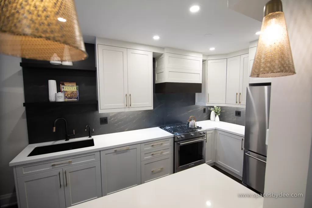 beautiful moody and bold kitchen with black, white, cream and gold accents with a bold backsplash and brown wood flooring.