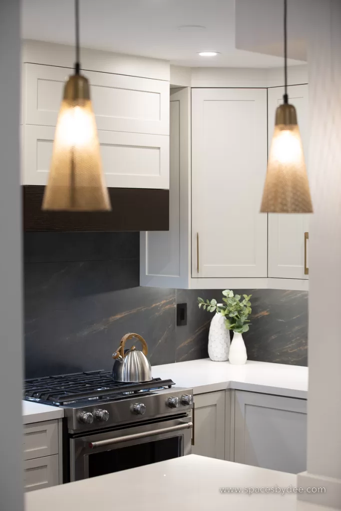 beautiful moody and bold kitchen with black, white, cream and gold accents with a bold backsplash and brown wood flooring.