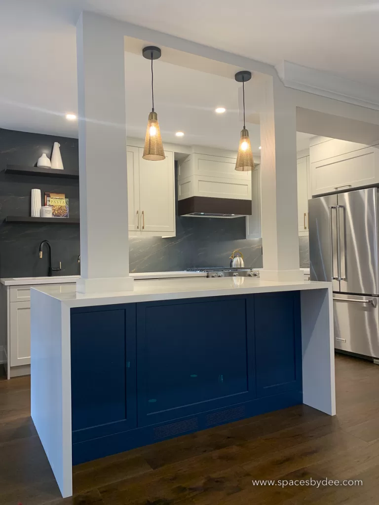 moody kitchen with blue island and black backsplash.