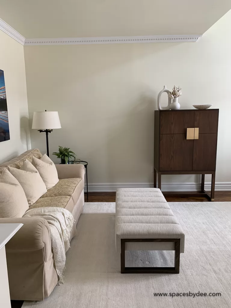 vintage and modern sitting/living room. The room uses vintage furniture. A vintage sofa, and modern rug, an ottoman and a wine cabinet.